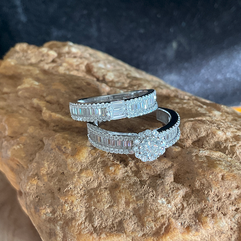 Two diamond rings on a textured stone surface with a dark background