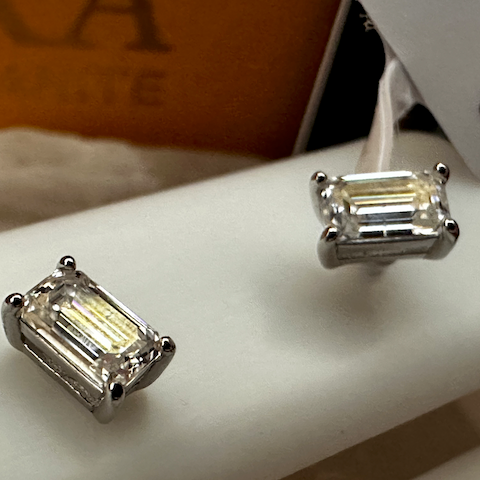 Pair of diamond stud earrings on a white surface with a blurred background