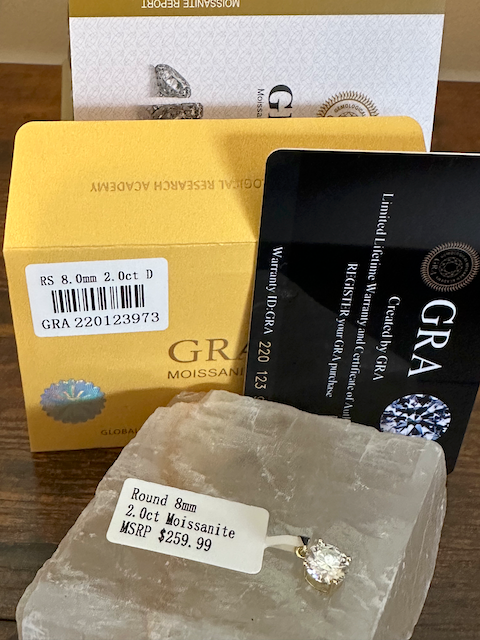 Moissanite stone with packaging and certification on a wooden surface