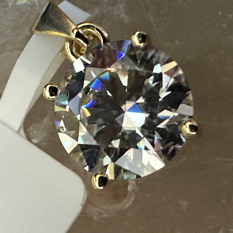 Gold pendant with a large diamond on a textured surface