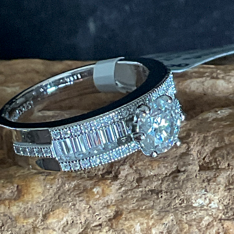 Silver ring with diamond accents on a textured stone surface
