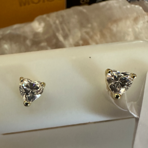 Heart-shaped diamond earrings on a white stand with a visible brand tag.