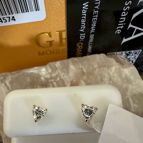 Trillion-cut gemstone earrings on a white stand with 'MOISSANTITE' label.