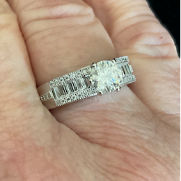 Hand wearing a diamond ring with a dark background