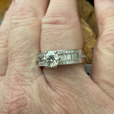 Silver ring with a large central gemstone on a person's finger