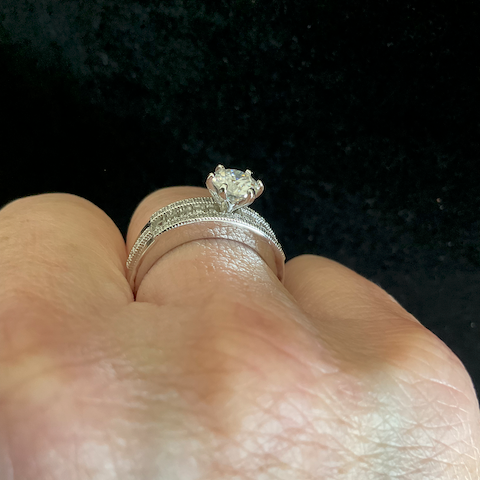 Close-up of a hand wearing two silver rings with a dark background