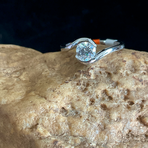 Silver ring with a diamond on a textured stone surface