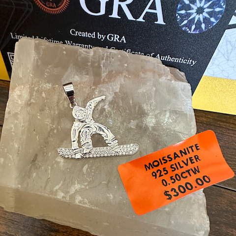 Silver pendant on a crystal with an orange tag displaying product details