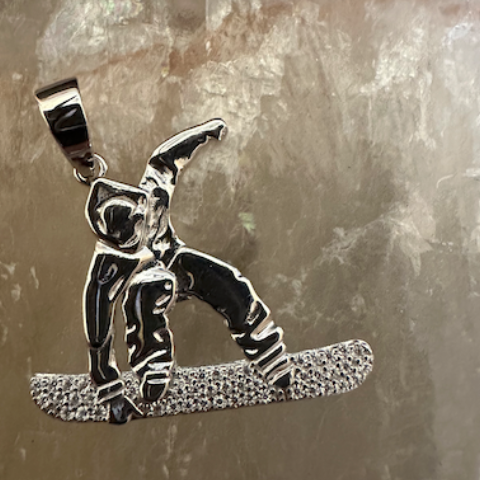 Silver snowboarder pendant on a stone surface with 'GRA' branding.