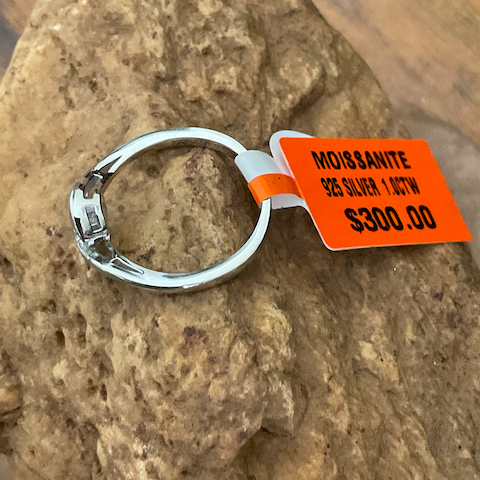 Silver ring with an orange tag on a rock