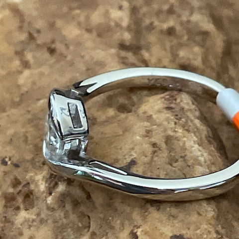 Silver ring with a diamond on a textured stone surface