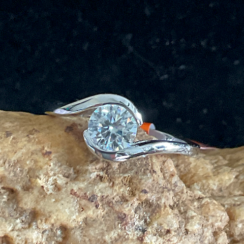 Silver ring with a diamond on a textured stone surface