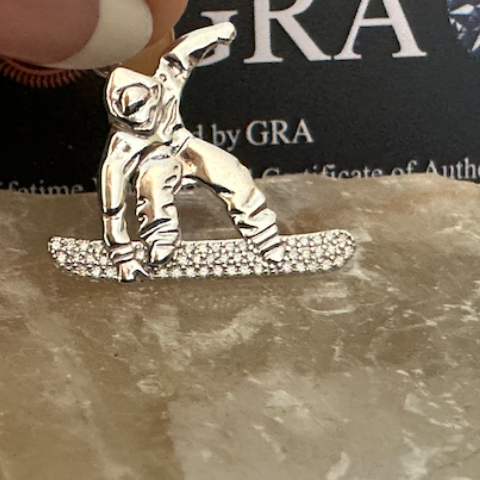 Silver snowboarder figurine on a rock with GRA certification in the background