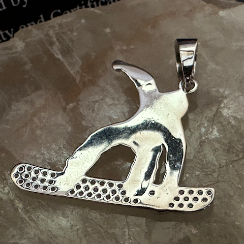 Silver dog pendant on a stone surface