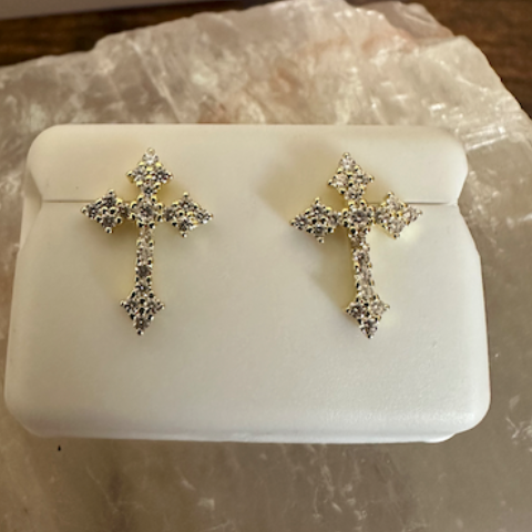 Silver cross-shaped earrings on a white stone surface