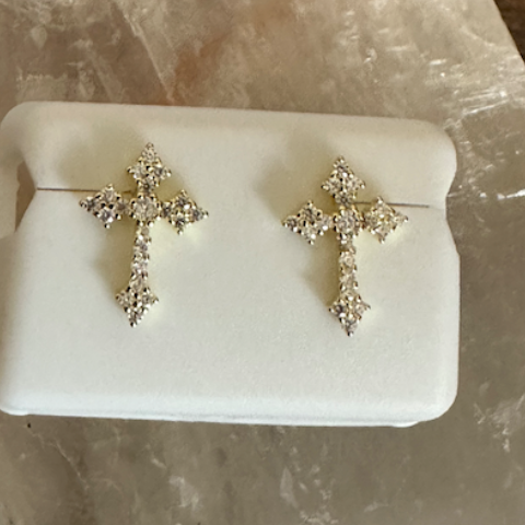 Pair of silver cross earrings on a white stone surface