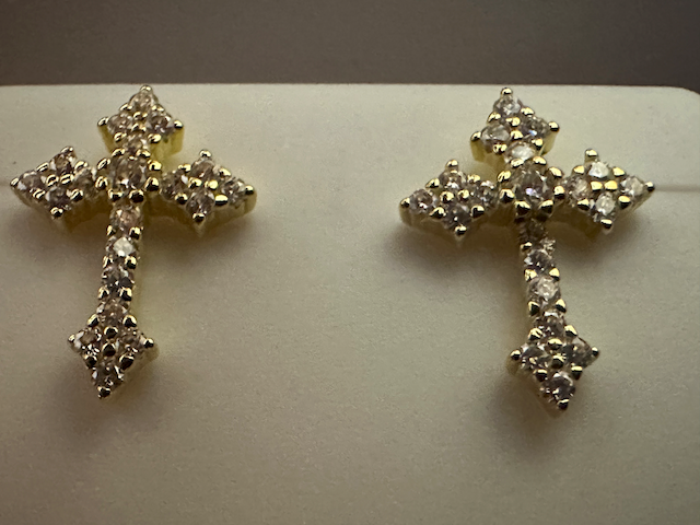 Pair of gold cross earrings on a light gray background