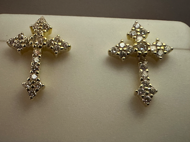 Pair of gold cross earrings with clear stones on a white background