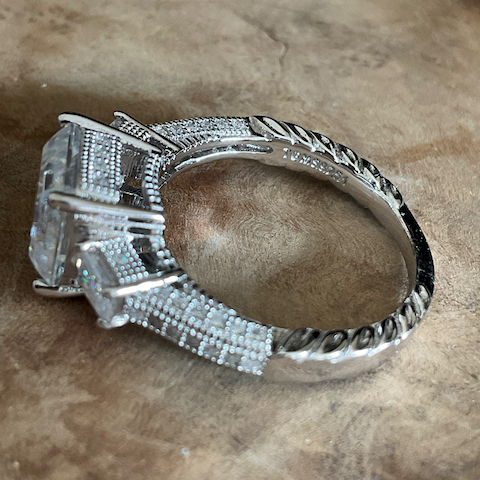 Silver ring with a large central stone on a textured surface