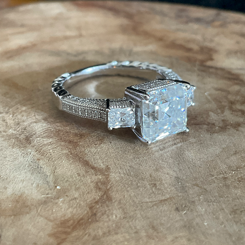 Silver ring with a large diamond on a wooden surface