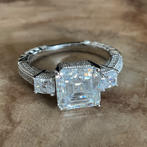 Silver ring with a large square-cut gemstone on a wooden surface