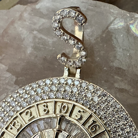 Close-up of a decorative clock face with gemstones on a reflective surface