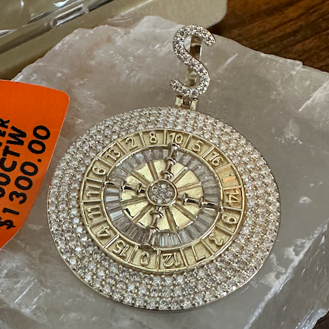 Gold and silver pendant with zodiac symbols on a clear plastic bag