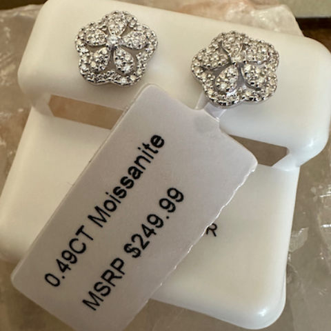 Silver flower-shaped earrings with a price tag on a white stand.