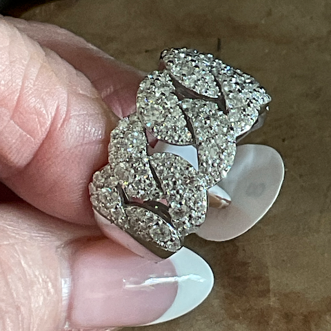 Close-up of a decorative brooch held by a hand on a textured surface
