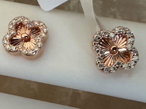 Rose gold floral earrings with clear gemstones on a white stand.