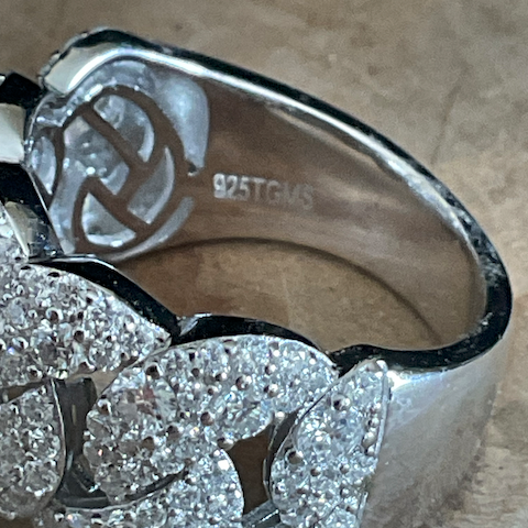 Silver ring with diamond-like stones on a textured surface