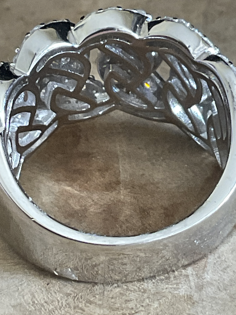 Silver ring with intricate design on a textured surface