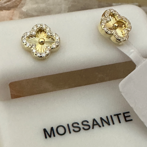 Gold earrings on a Moissanite branded stand with a clear background