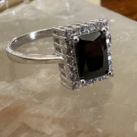 Silver ring with a black gemstone on a marble surface