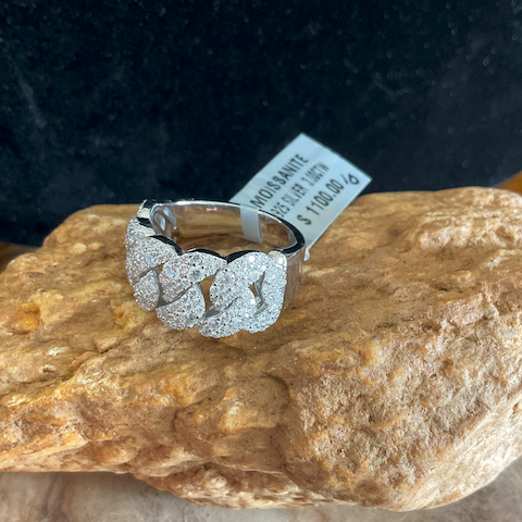 Silver ring with intricate design on a rock