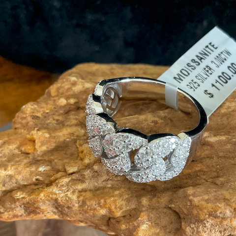 Silver ring with gemstones on a rock, price tag visible
