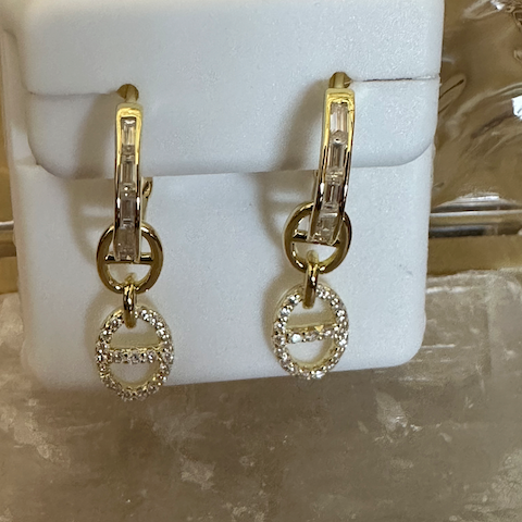 Gold earrings with circular designs on a white stand.