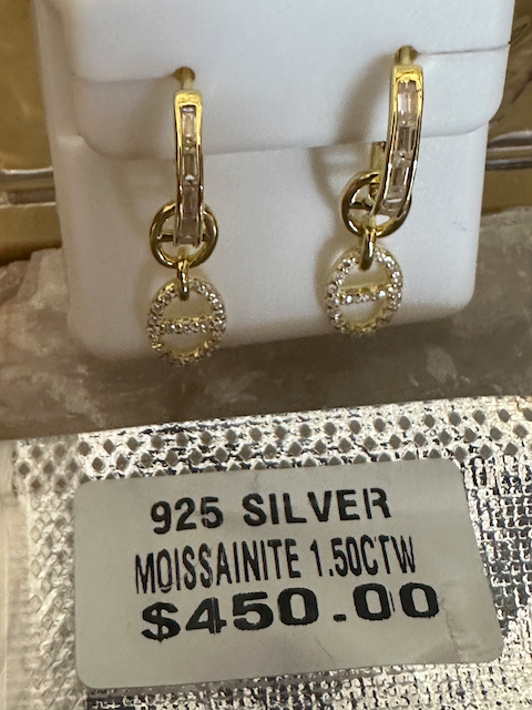 Gold earrings with a price tag on a textured surface