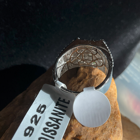 Silver ring with '925 Moissanite' label on a stone surface