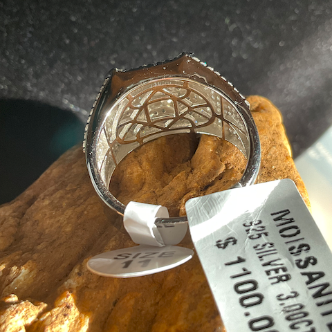 Silver ring with intricate design on a rock, accompanied by a price tag.