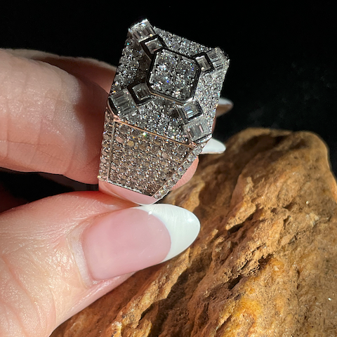 Diamond ring held by a hand on a textured surface