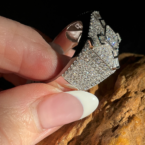 Diamond earring held between fingers against a textured surface