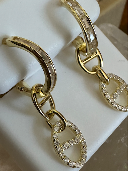 Gold hoop earrings with chain and circular design on a white stand.