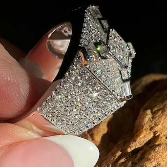 Diamond ring held between fingers against a textured surface