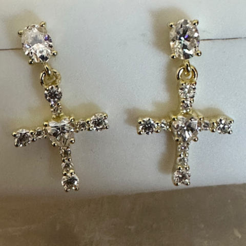 Gold cross earrings with clear stones on a white jewelry display box.