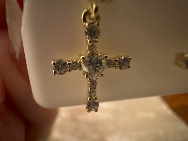 Gold cross pendant with diamonds on a white card