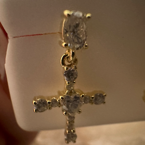 Gold cross earring with clear gemstones on a white background