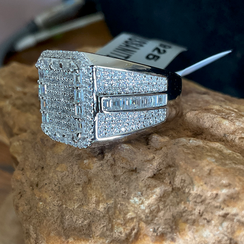 Silver ring with gemstones on a rock