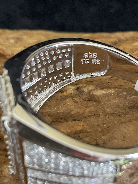 Close-up of a silver ring with '925' stamp on a wooden surface