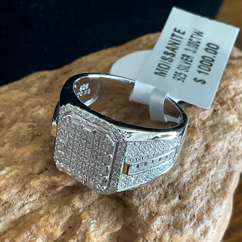 Silver ring with gemstones on a rock with a price tag